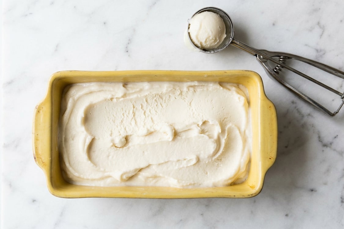 Buttermilk sorbet in loaf pan with an ice cream scoop. 