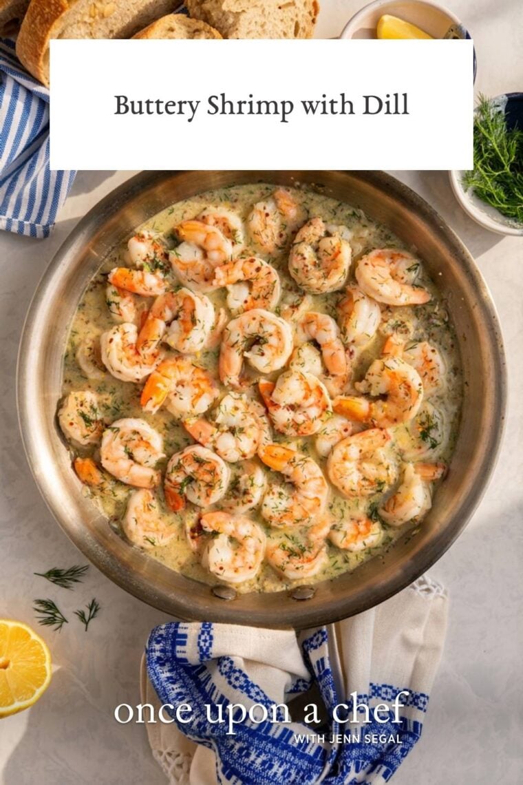 buttery shrimp with dill in a large skillet with a basket of bread nearby