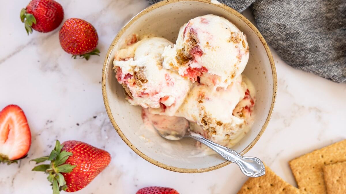 bowl of no churn strawberry ice cream with graham crackers and strawberries nearby