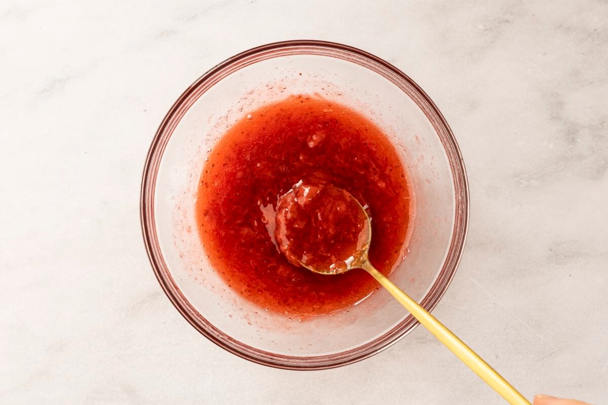 spoon stirring cooked strawberry mixture in small bowl