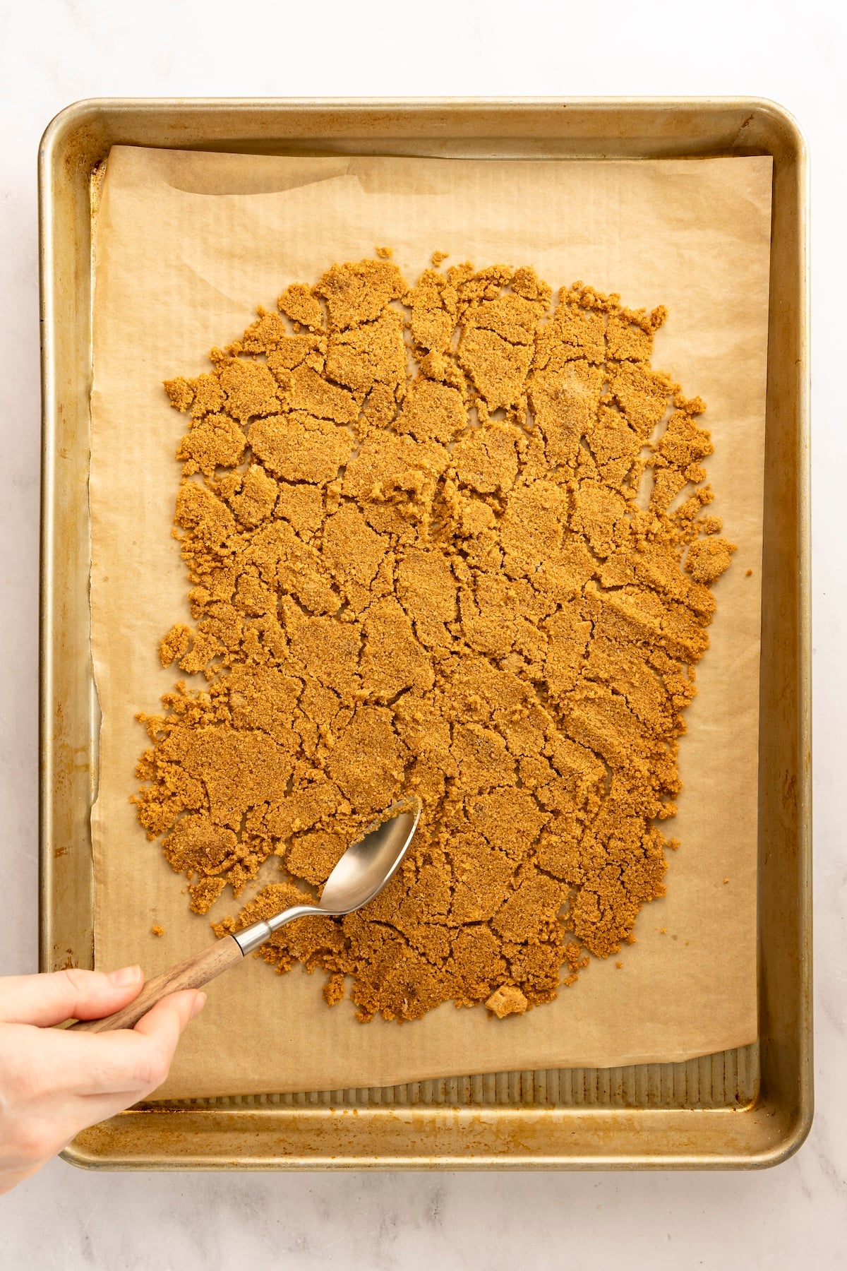 prepared baking sheet with graham cracker crust broken into chunks with spoon