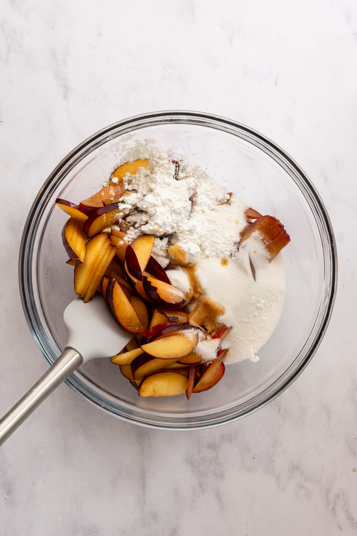 Large bowl with plums, granulated sugar, cornstarch, vanilla, and salt added