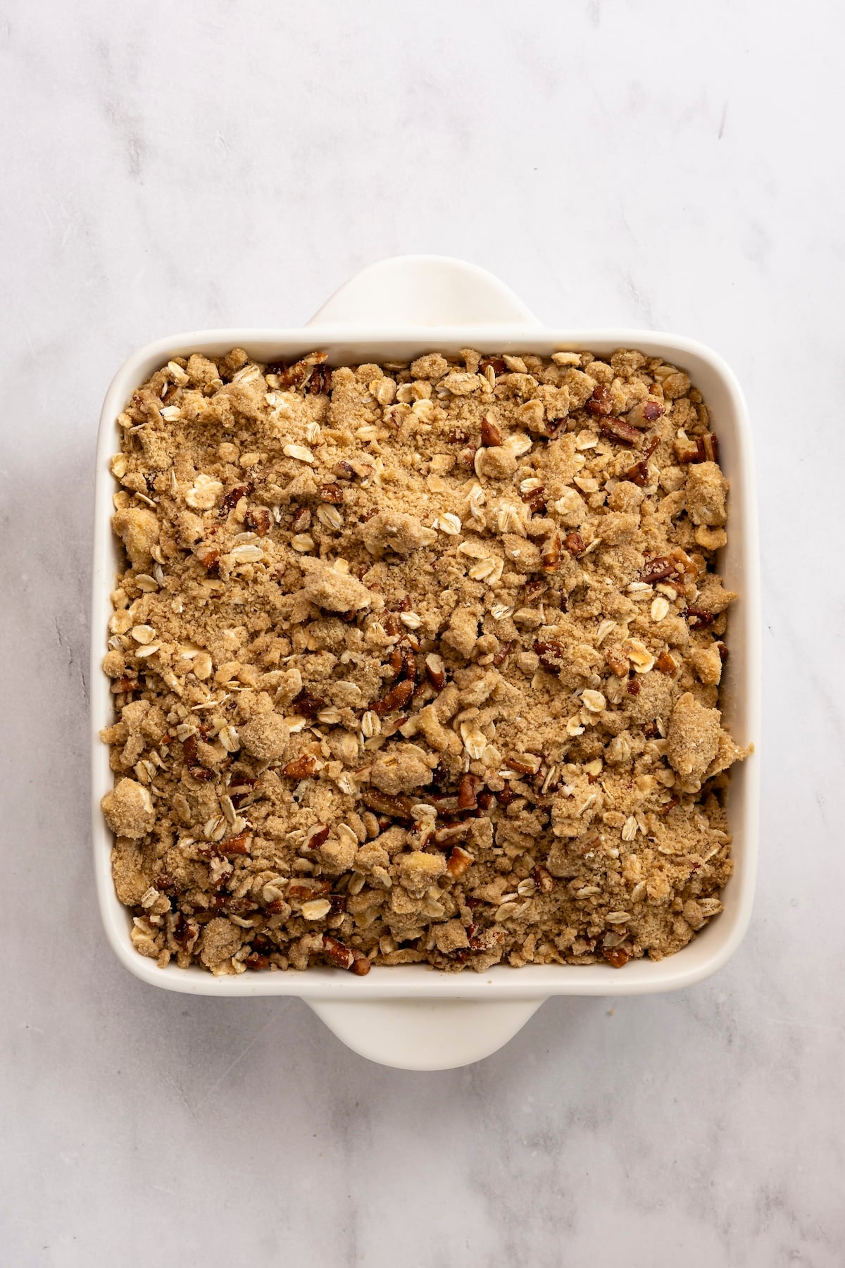 8-inch baking dish with unbaked plum oat pecan crisp