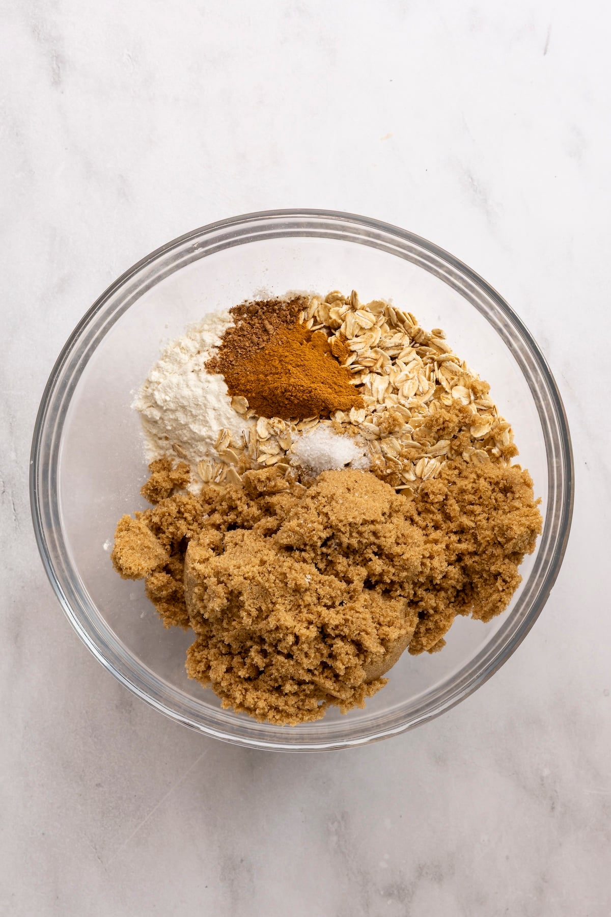 medium bowl with flour, oats, brown sugar, cinnamon, nutmeg, and salt added