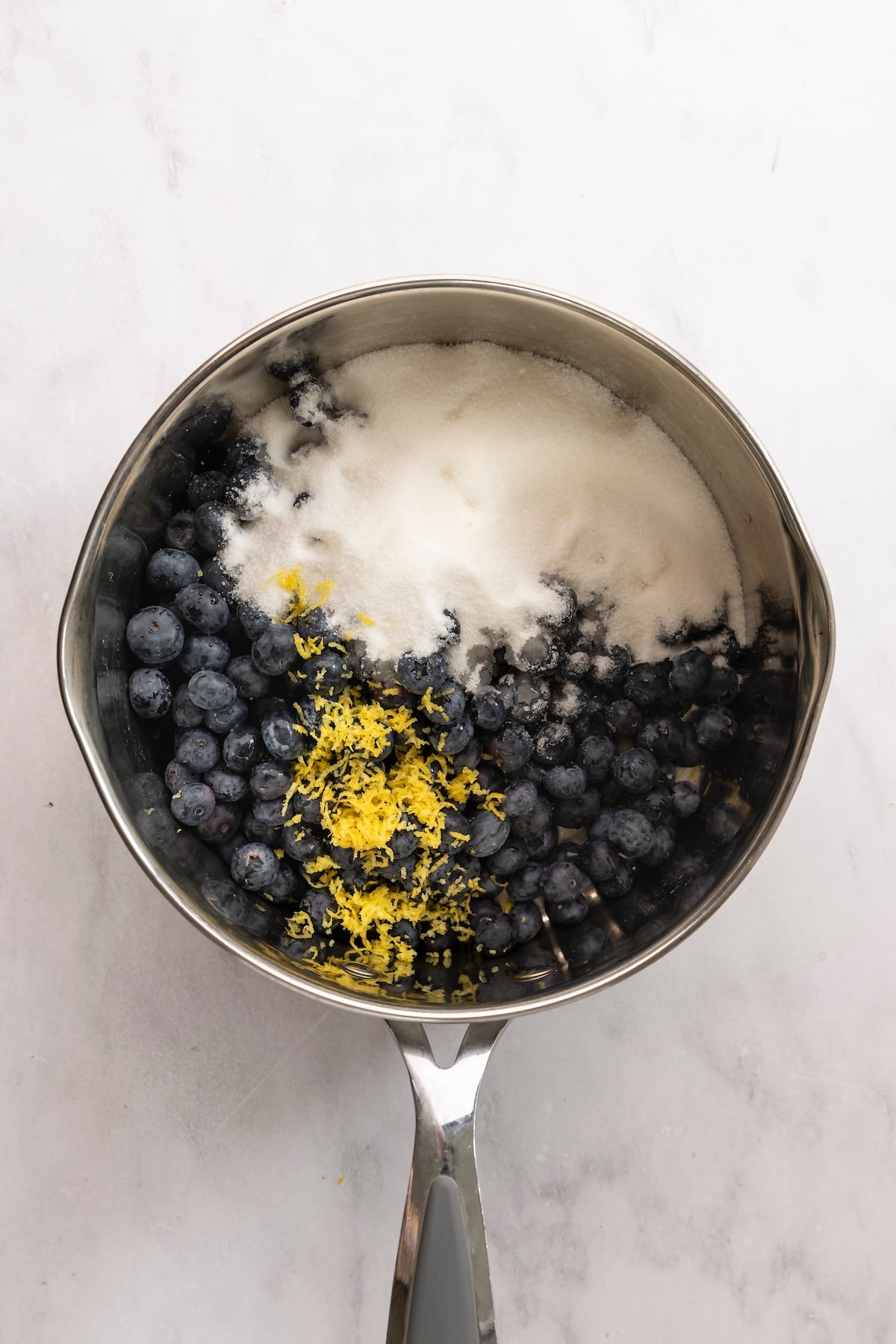 Blueberries, sugar, and lemon zest in pot.