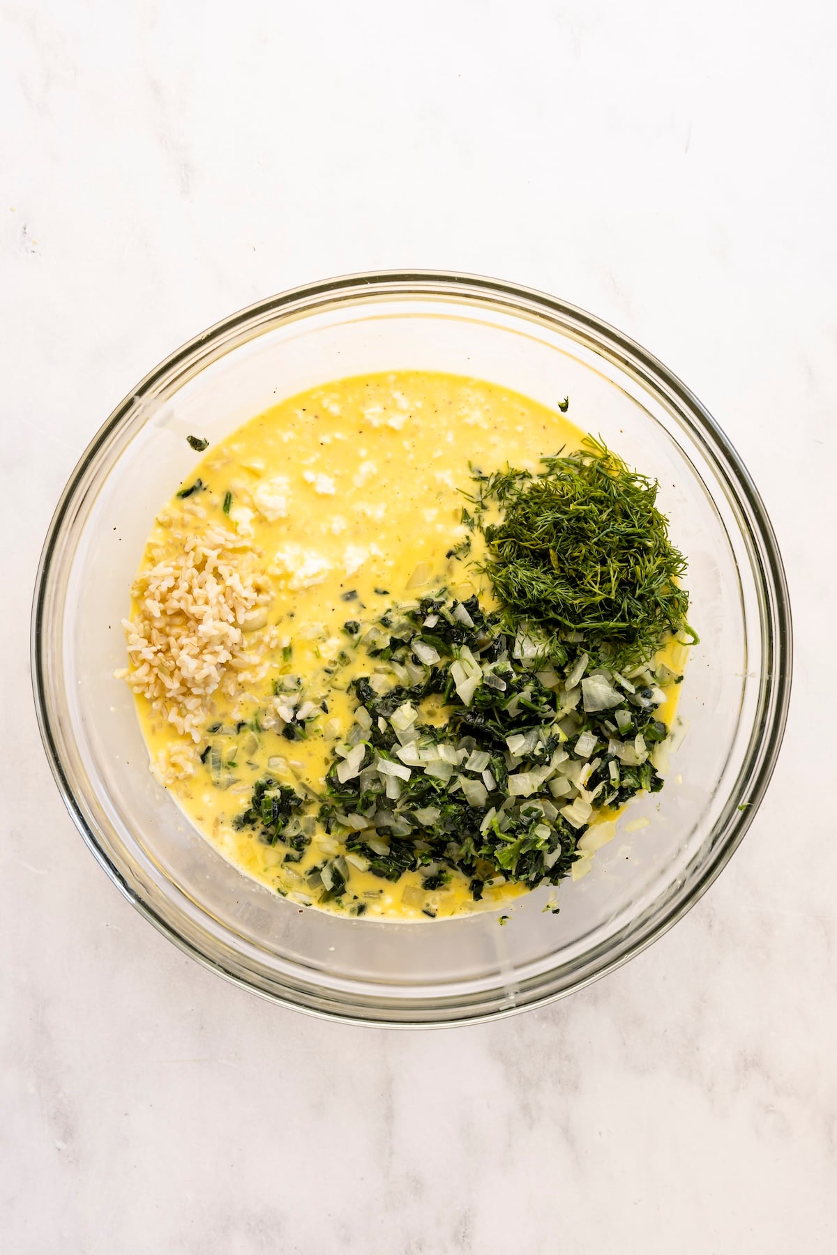 large bowl with rice, feta, dill, and onion-spinach mixture added to egg mixture