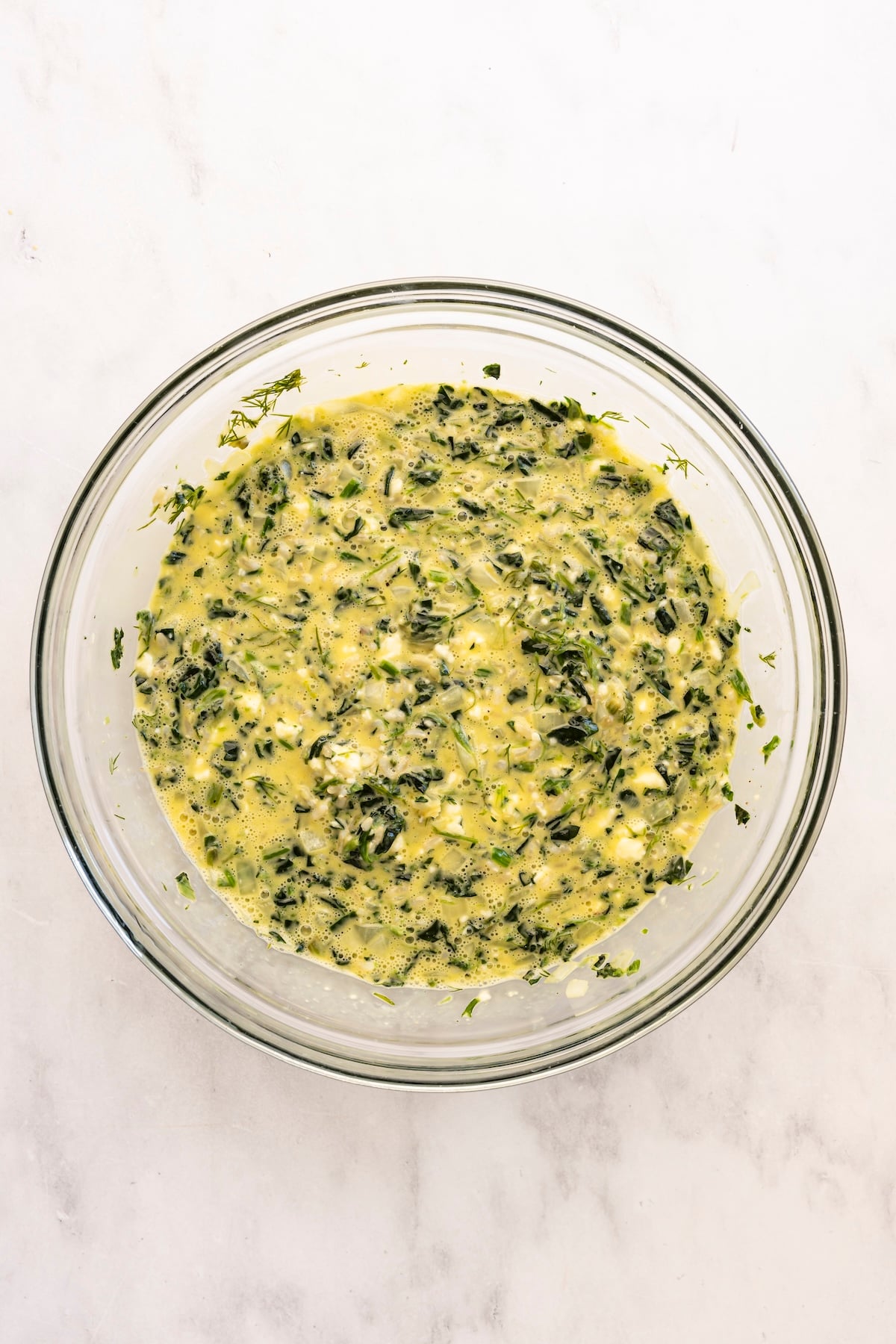 large bowl with rice, feta, dill, and onion-spinach mixture combined with egg mixture