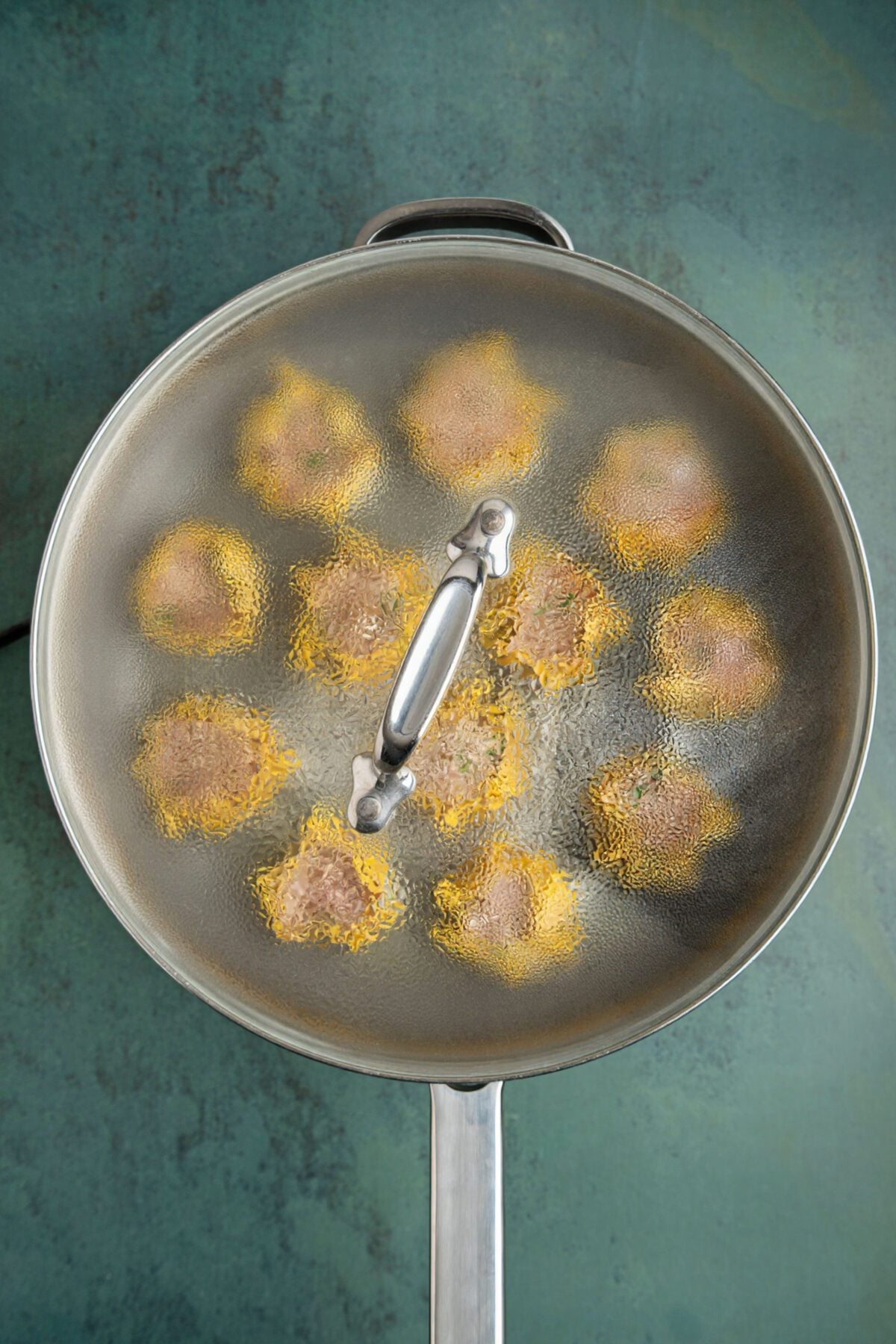 Lid on non-stick pan containing dumplings