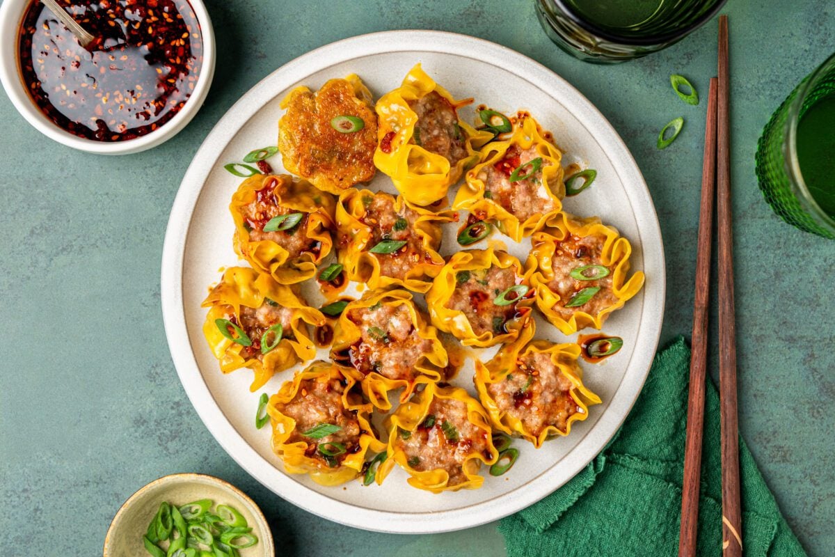 white serving platter with skillet dumplings topped with sliced scallions and drizzled with sauce