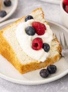 Slice of angel food cake with whipped cream and berries.