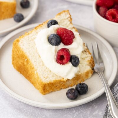 Slice of angel food cake with whipped cream and berries.