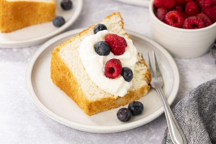 Slice of angel food cake with whipped cream and berries.