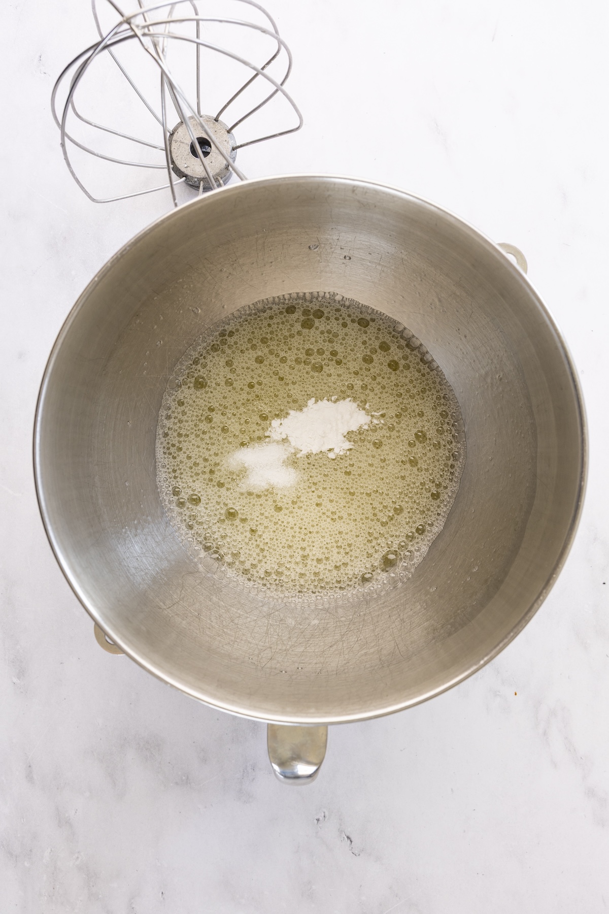 mixing bowl with cream of tartar and salt added to foamy egg whites 