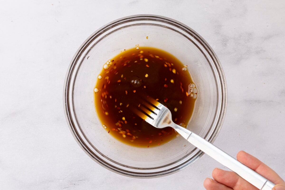 Mixing sauce for Szechuan green beans with fork.