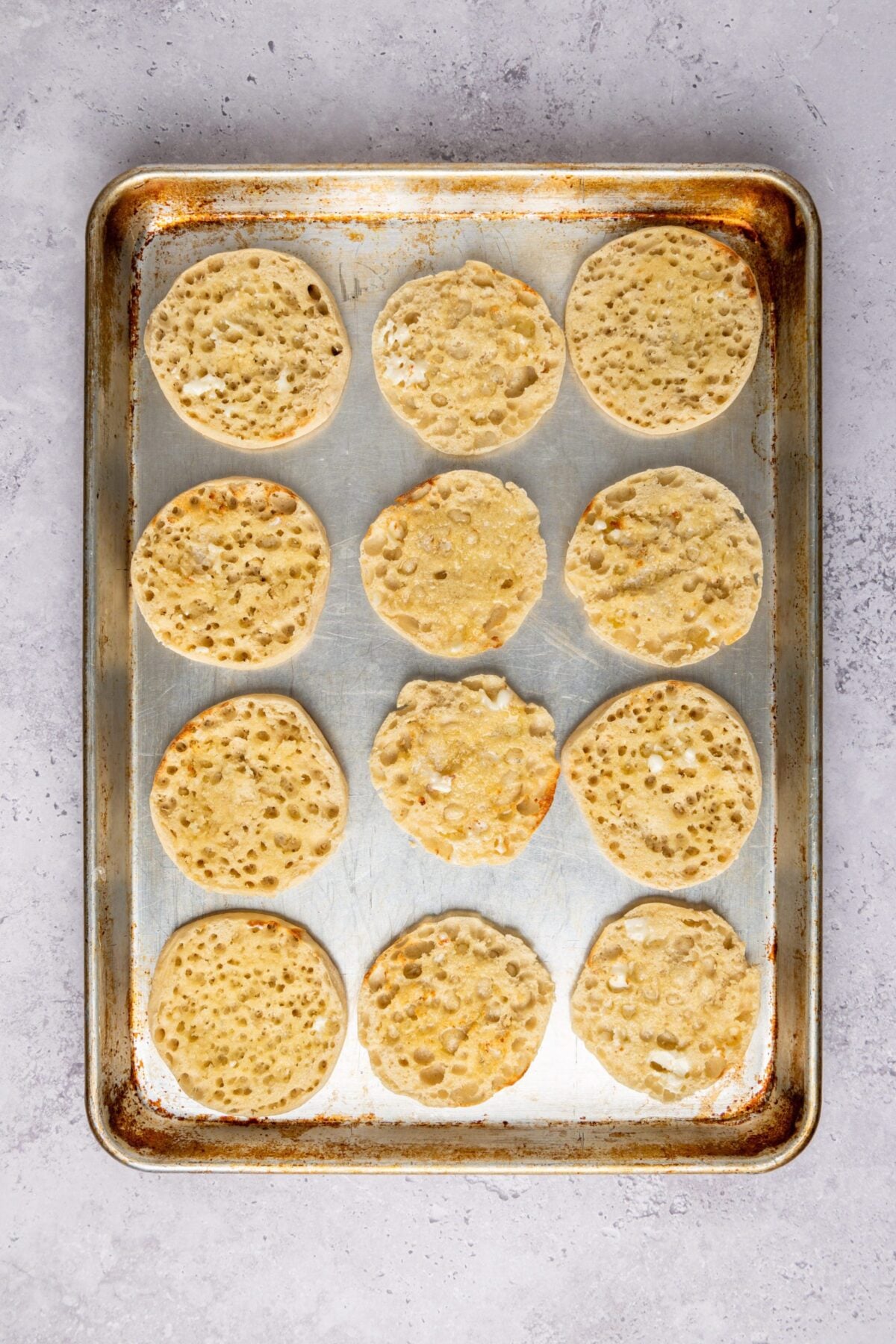 Lightly buttered toasted English muffin halves on baking sheet 