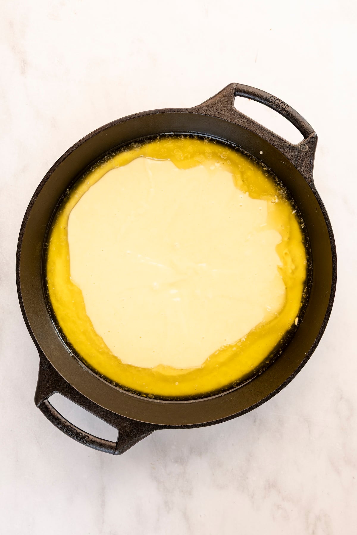 cast iron skillet with buckle batter poured over melted butter