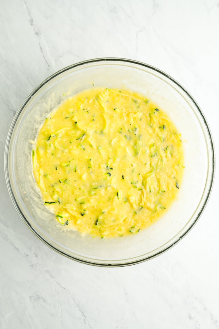 shredded zucchini added to egg mixture in bowl