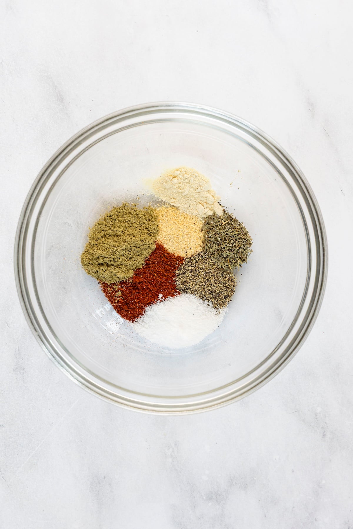 SMALL BOWL WITH PILES OF SALT, PAPRIKA, SAGE, THYME, BLACK PEPPER, GARLIC POWDER, AND ONION POWDER