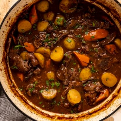Beef stew in Dutch oven on wood table.