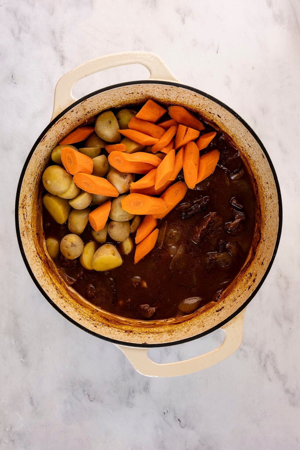 Carrots and potatoes added to partially cooked stew.
