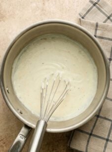 Bechamel sauce in pot with whisk.