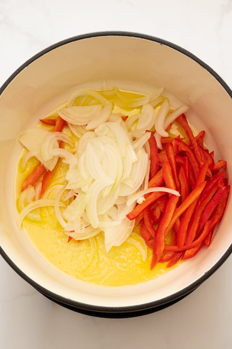 Onions and bell pepper added to olive oil in Dutch oven.